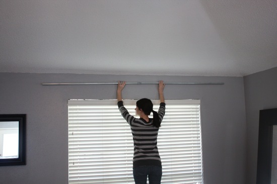 Woman installing a DIY conduit curtain rod