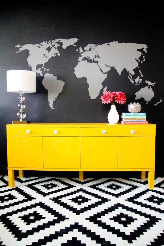 a yellow sideboard against a black wall with a map mural painted on the wall