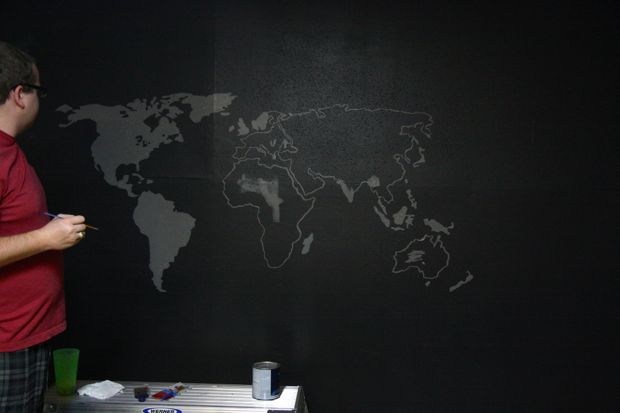 man painting a map wall mural with projector