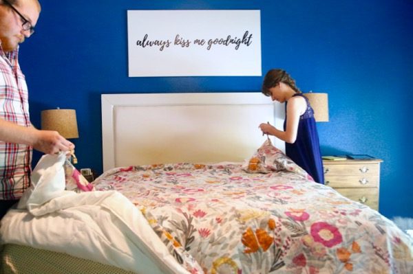 Man and woman tying the ends of a duvet cover