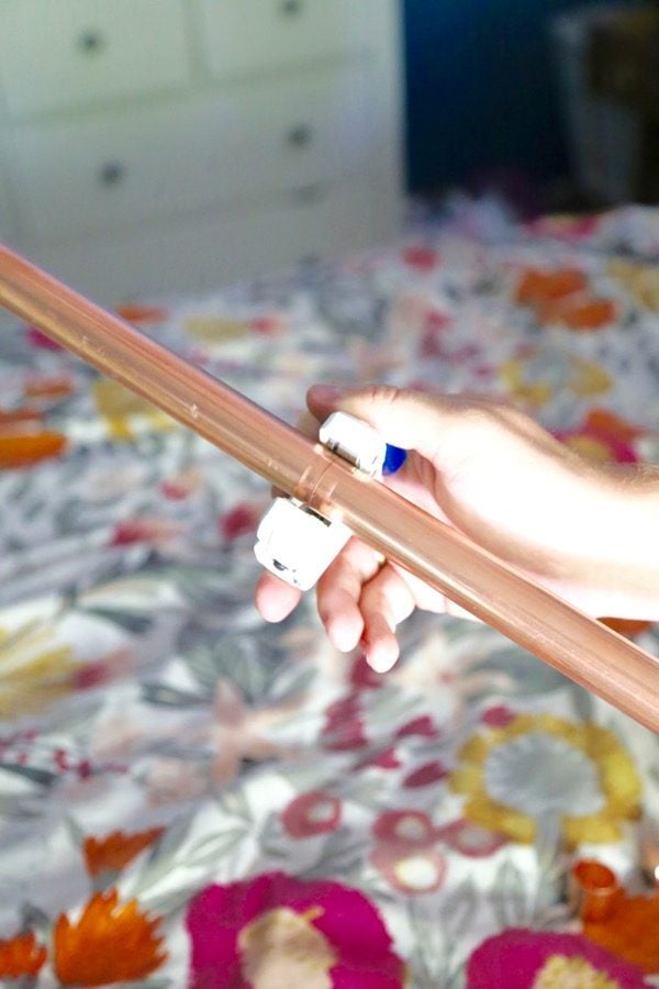 woman's hand using a pipe cutter to cut a copper pipe