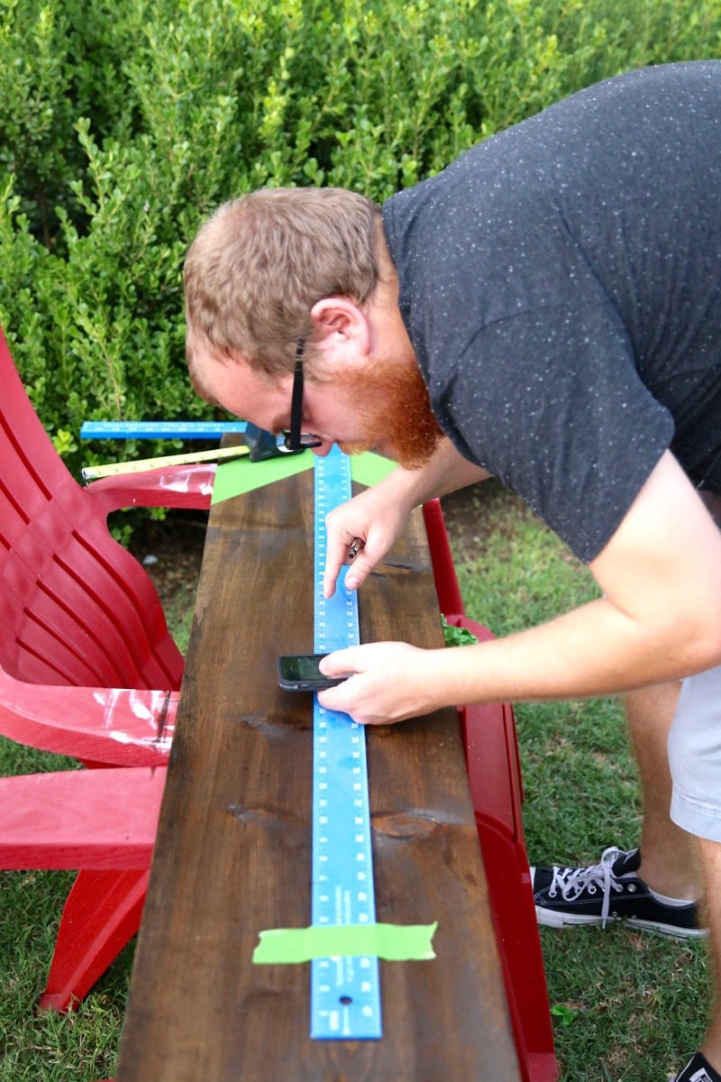 A man marking measurements on a large piece of wood to create a growth chart