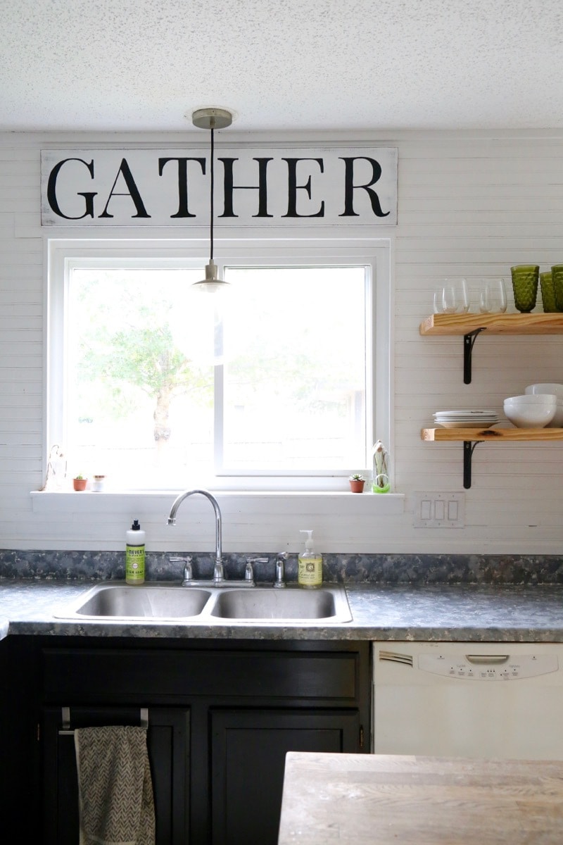 Kitchen with a DIY Wood gather sign above the sink 