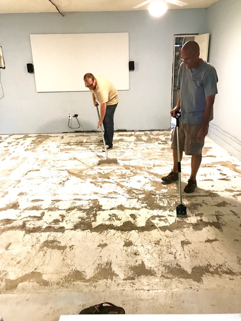 man scraping paint off a garage floor 