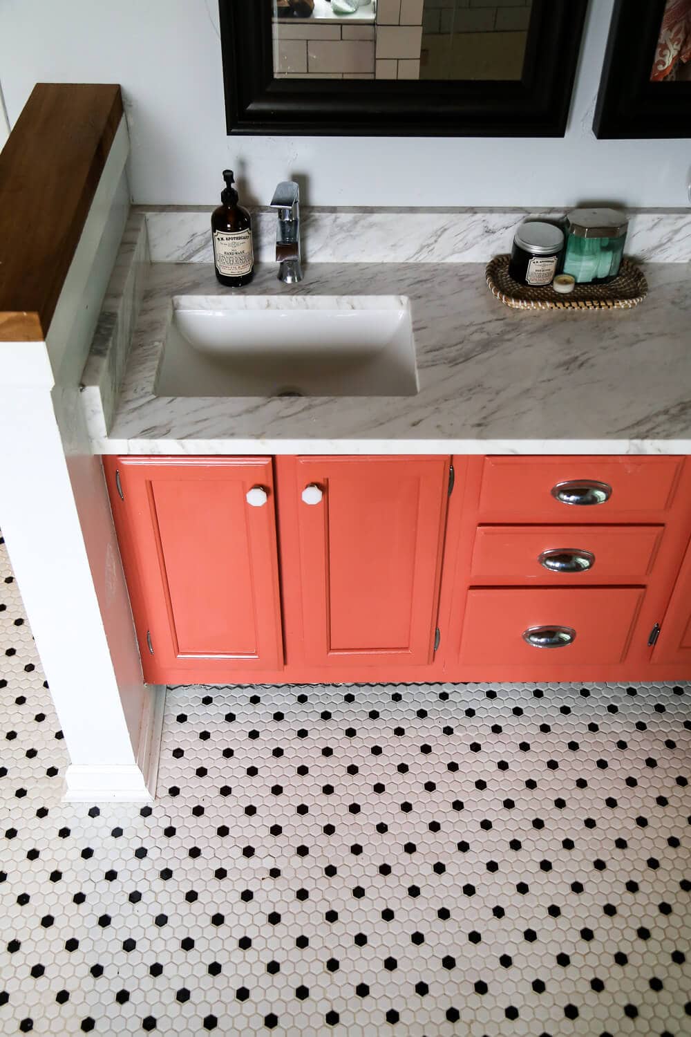 Overhead shot of master bathroom remodel - black and white hex tile, coral vanity, and quartz countertop