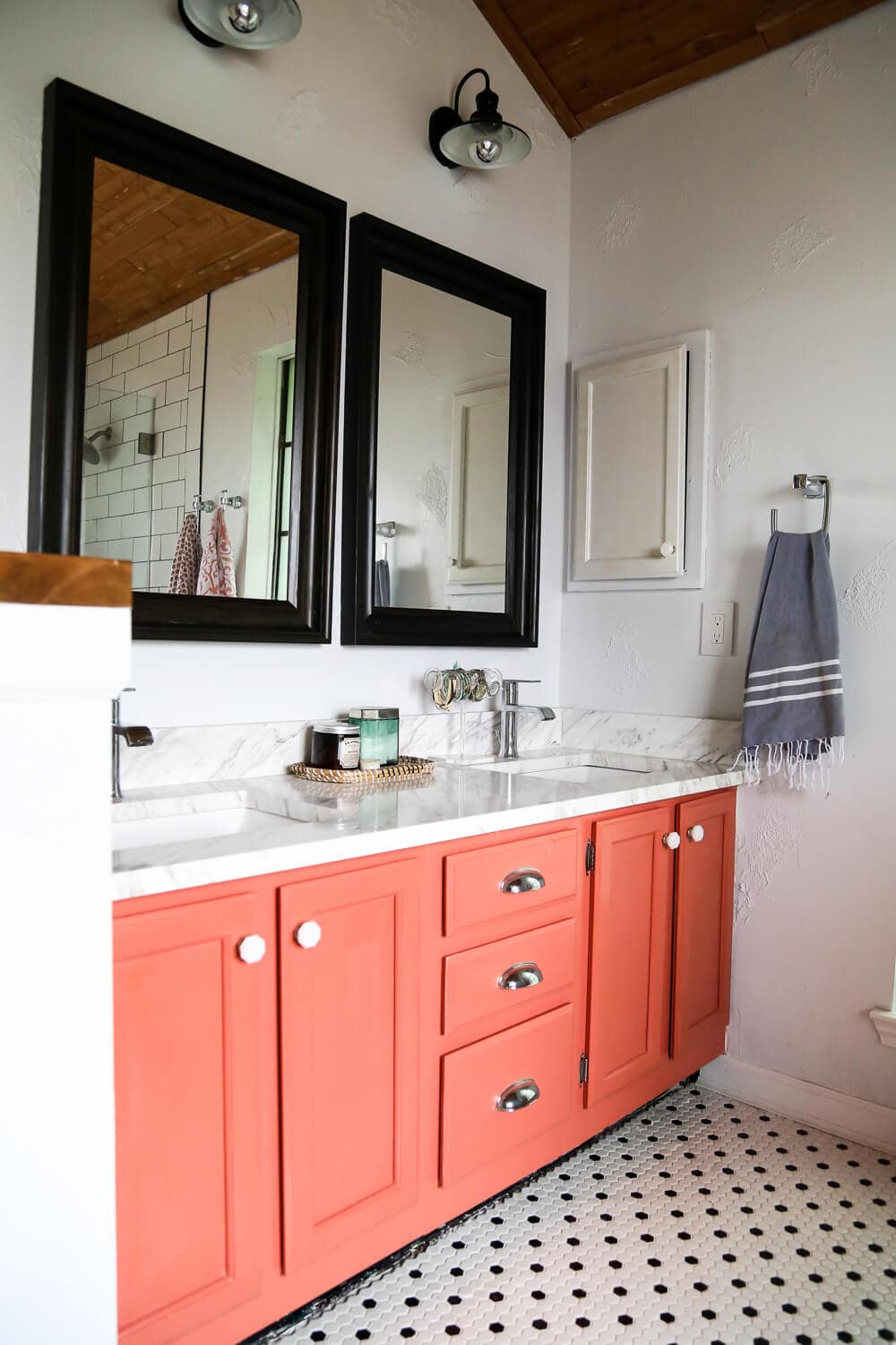 A master bathroom remodel with a coral vanity and black and white hex tile on the floor