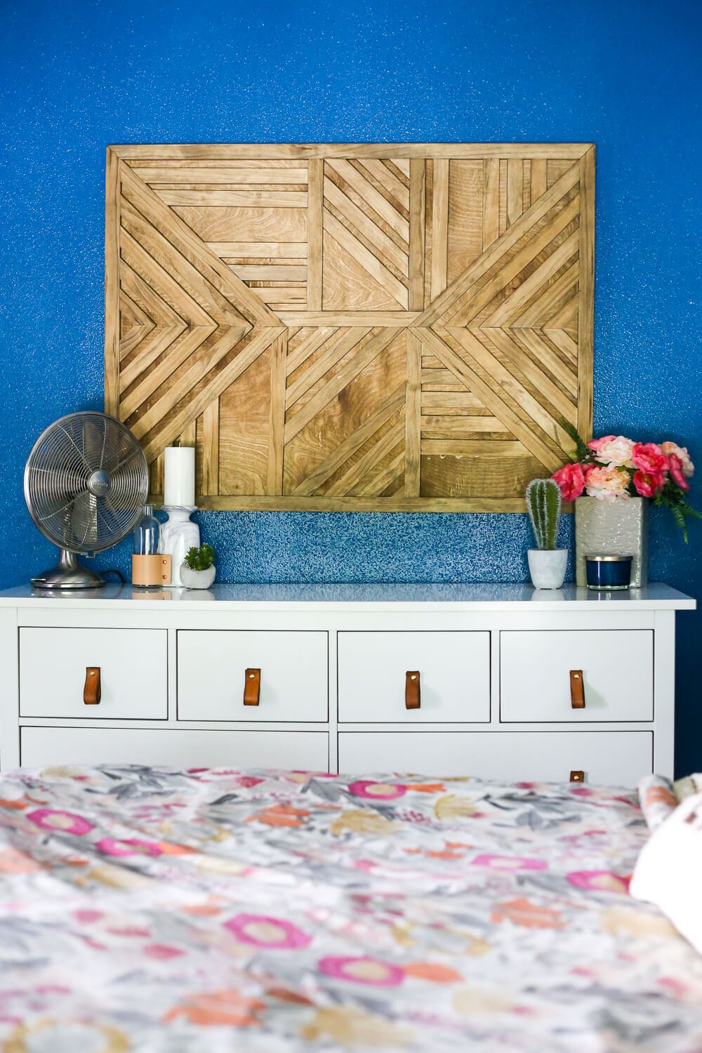 Bedroom with a white dresser and geometric wall art hanging above the dresser 