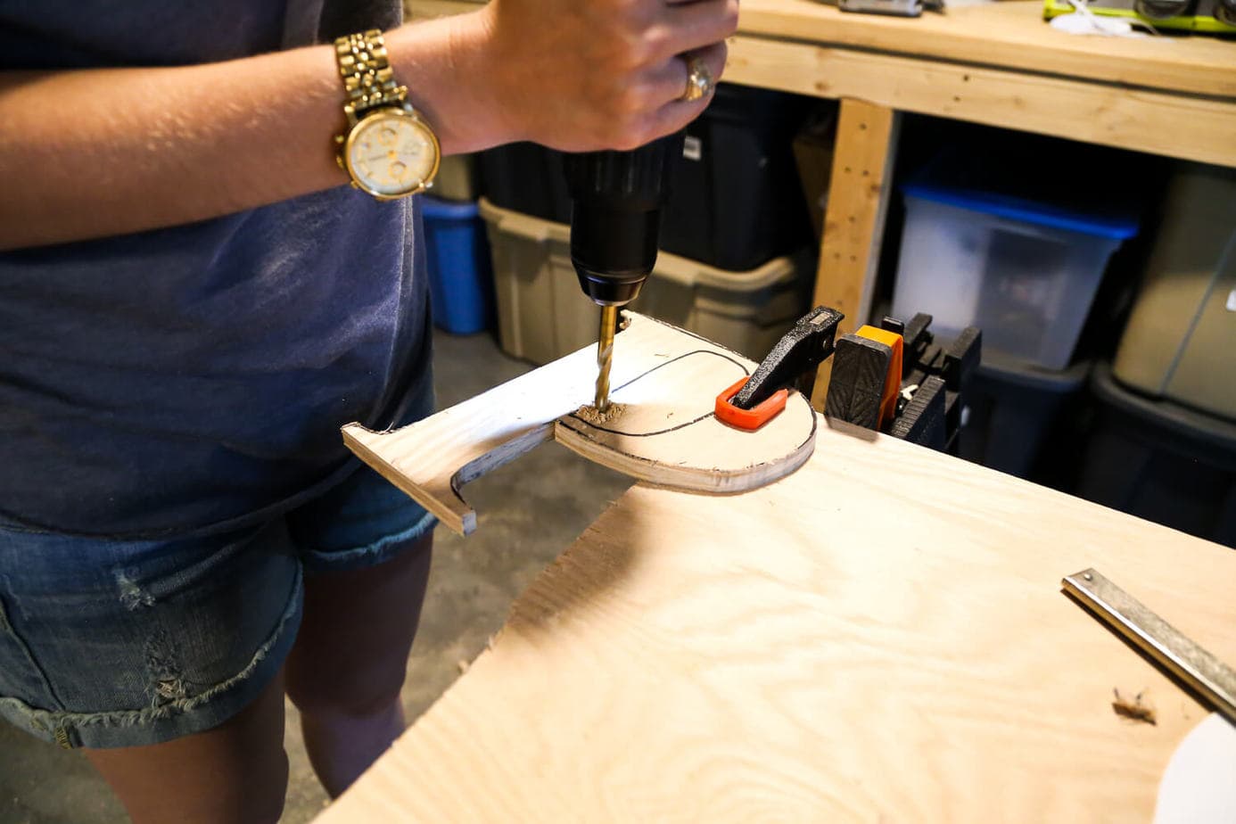 woman using a drill to create a hole in a piece of plywood