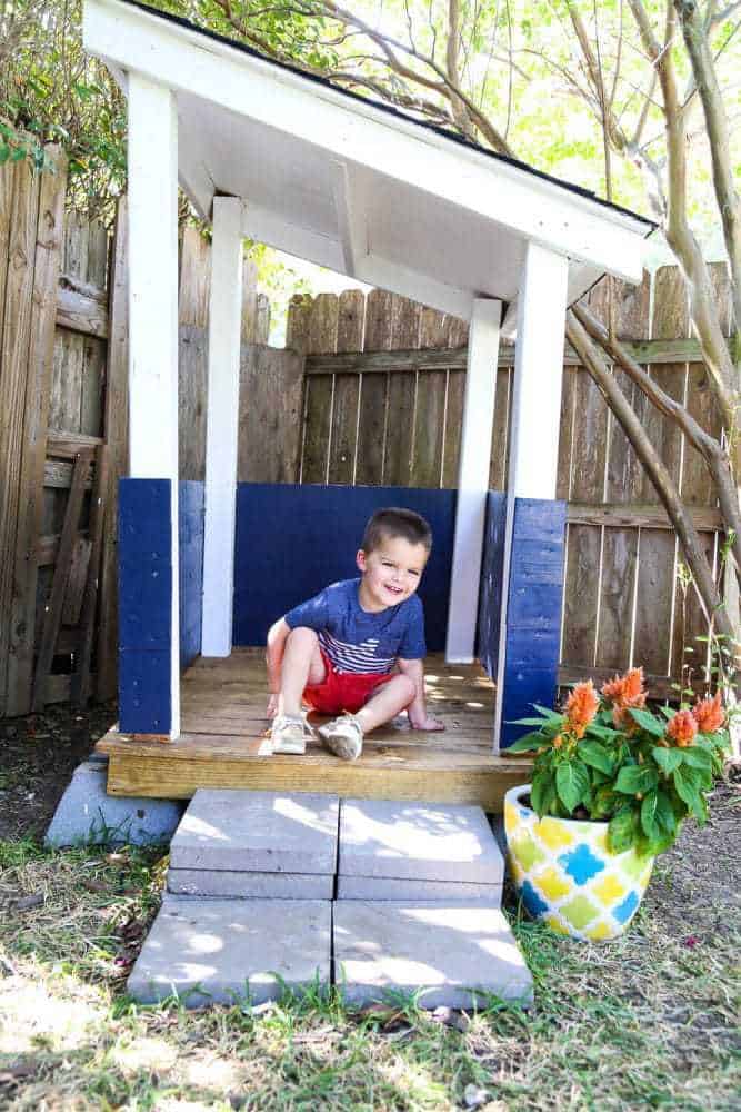 a toddler in a DIY outdoor playhouse