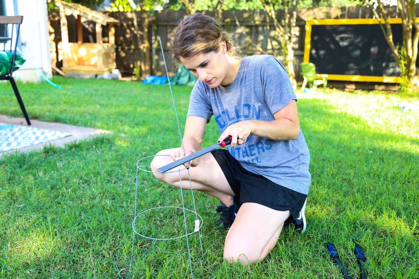 Clipping ends off of tomato cage for DIY wire plant stand