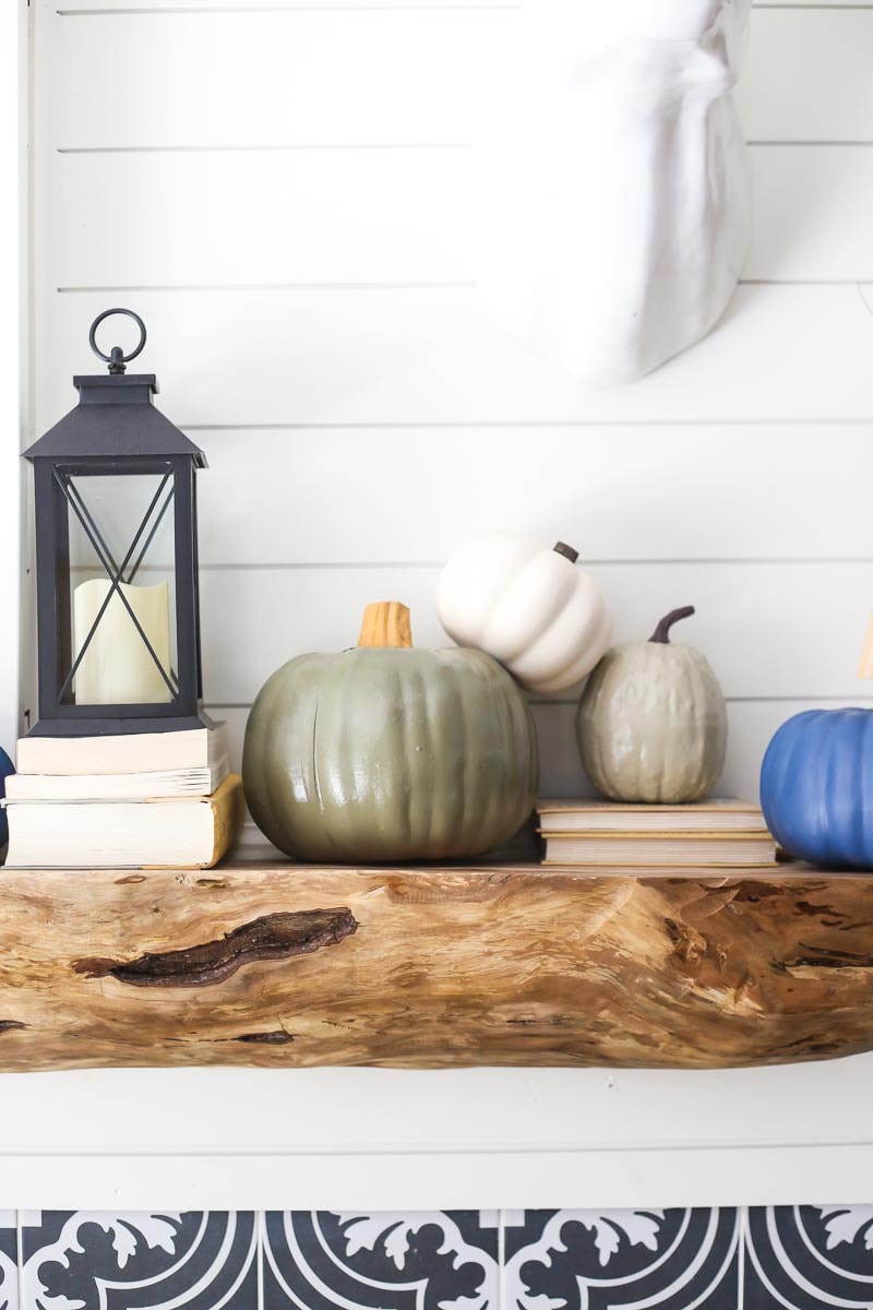 a mantel decorated for fall with faux painted pumpkins