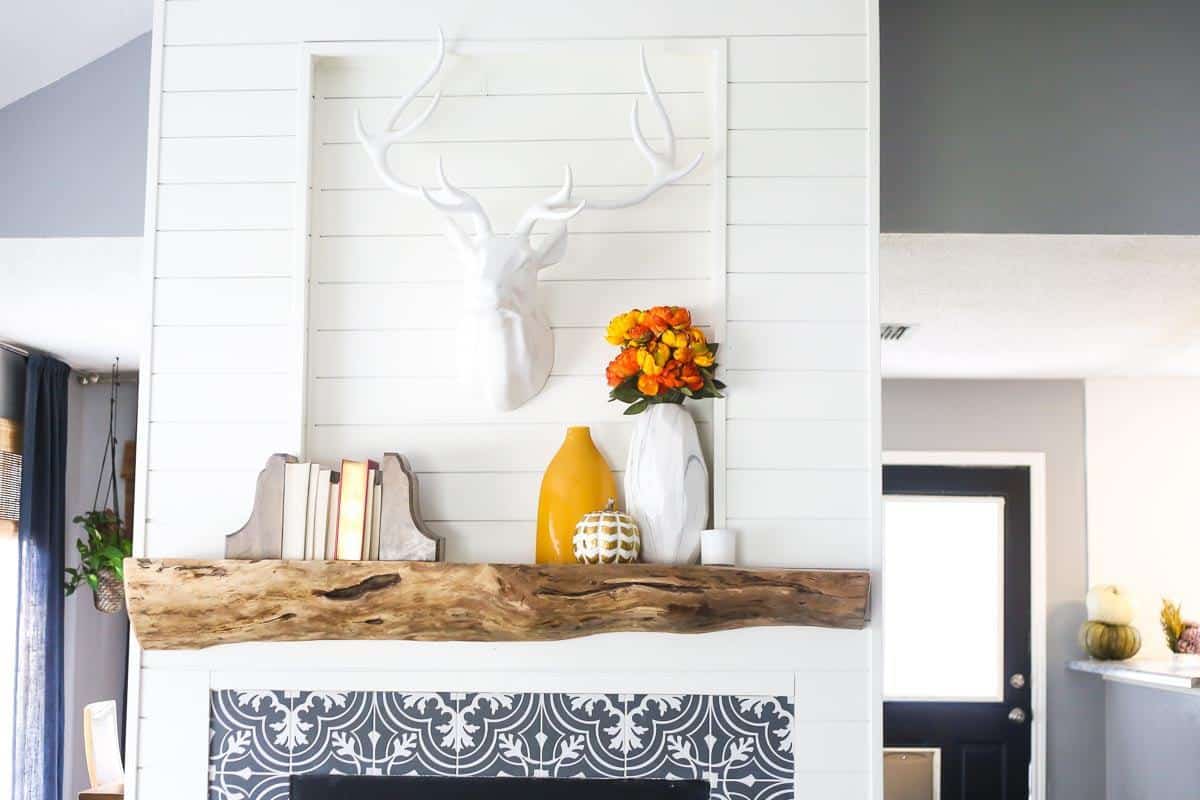 a shiplap fireplace with a rustic wood mantel made from a tree stump