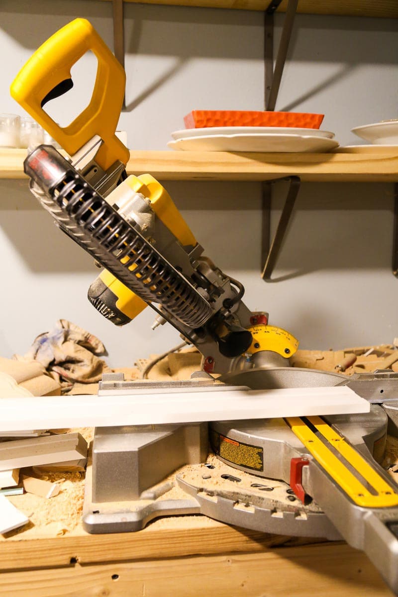 miter saw with a piece of baseboard being cut 