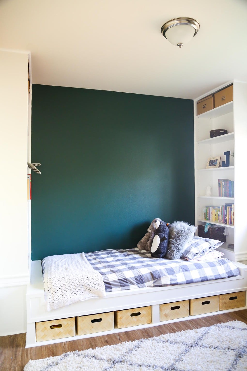 Platform bed with floor-to-ceiling bookcases and a green accent wall