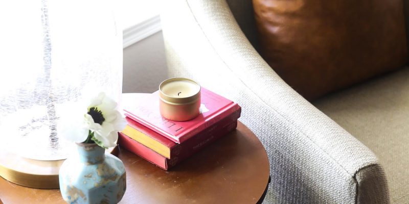 Round side table with books, a lamp, and a candle
