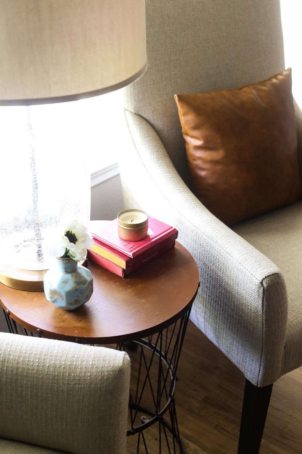 Round side table with books, a lamp, and a candle