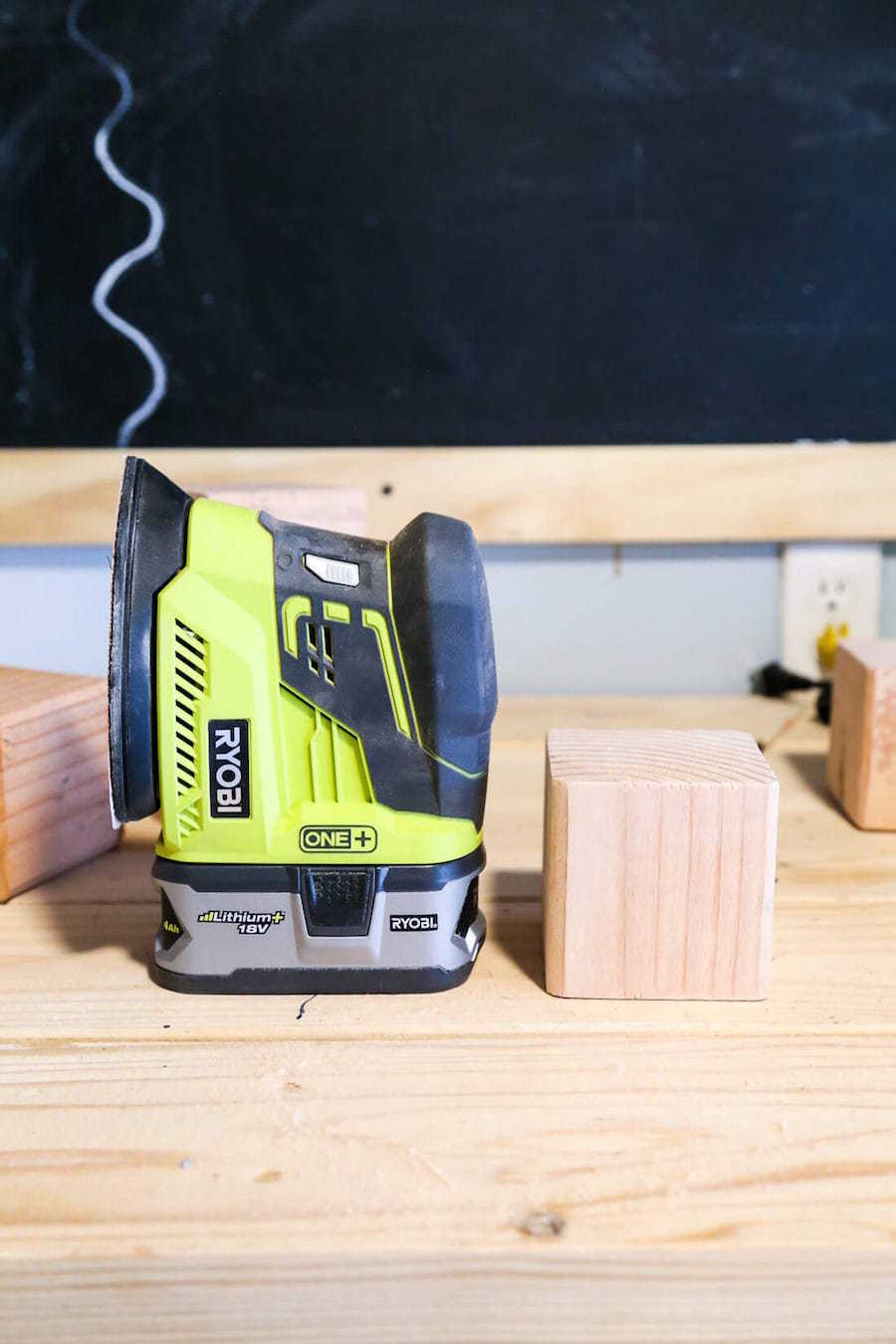 unfinished wood dice next to a power sander