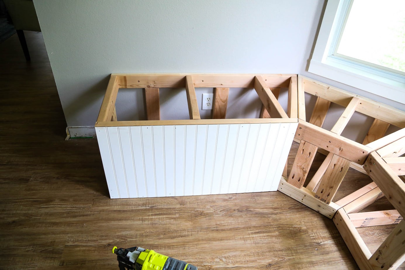 Framing for bay window bench with beadboard being installed on the front