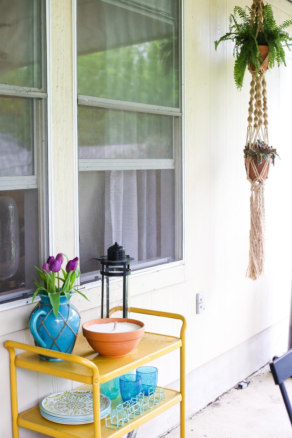 Yellow backyard bar cart with a large candle, purple tulips, and a black lantern