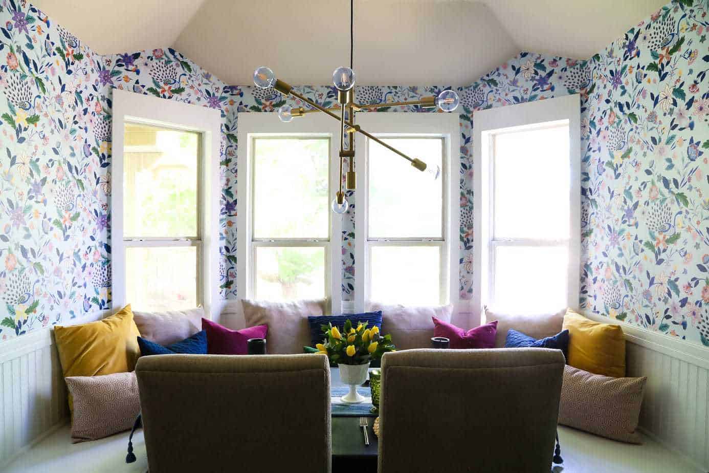 a breakfast nook with bright floral wallpaper and a built-in banquette