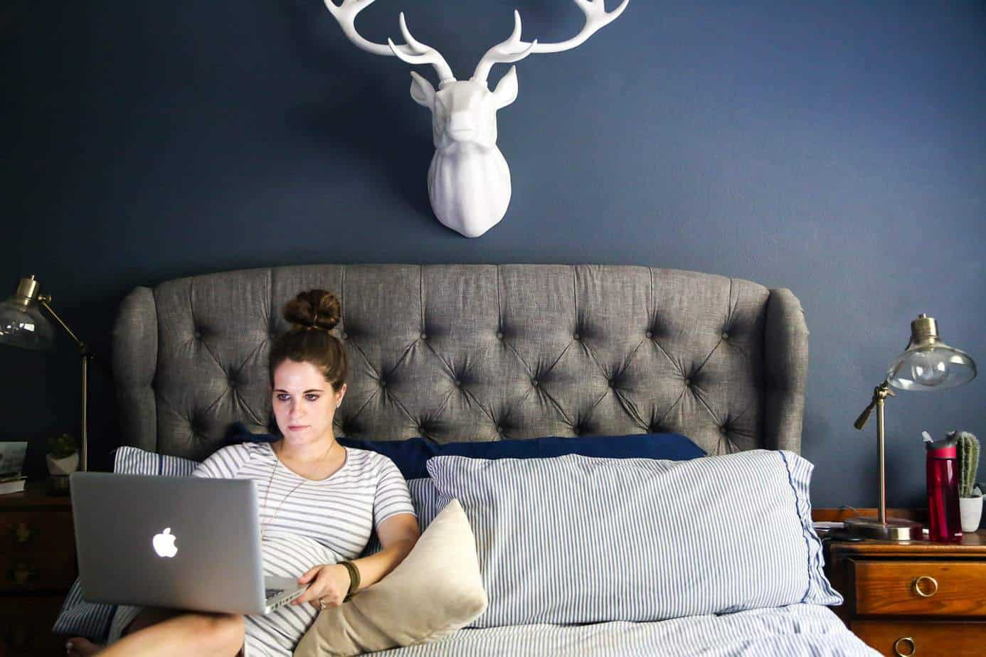 woman sitting on a bed with laptop