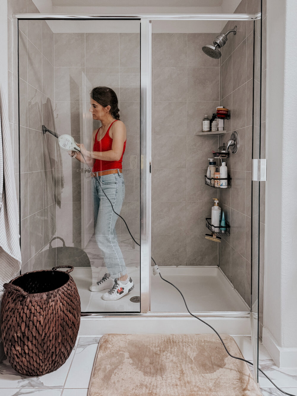 Woman using a Bissell steam cleaner to clean the grout in a tile shower