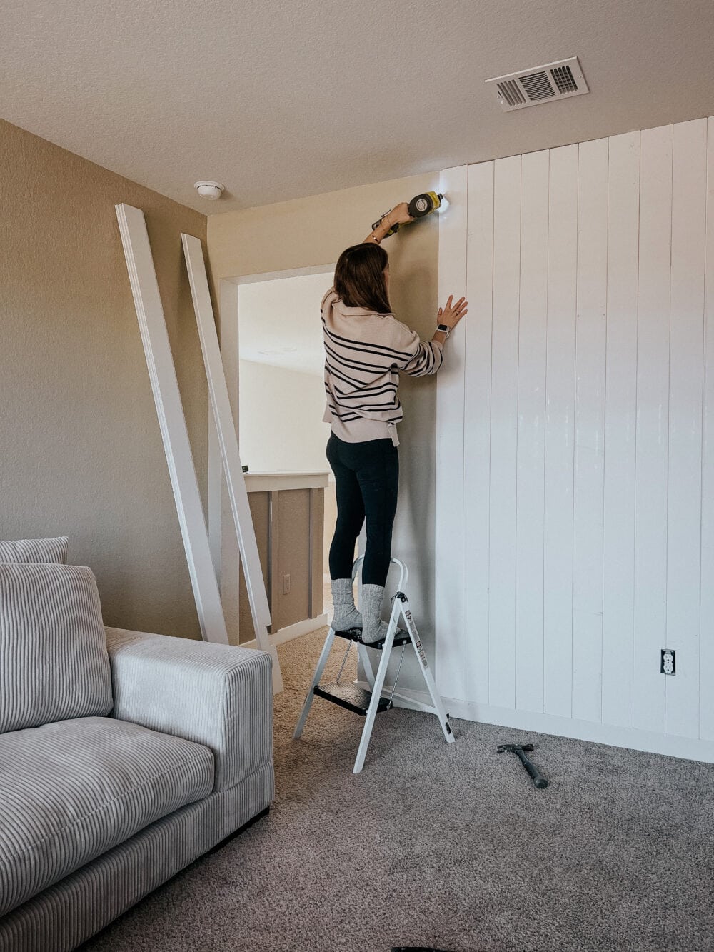 woman using a nail gun to install shiplap