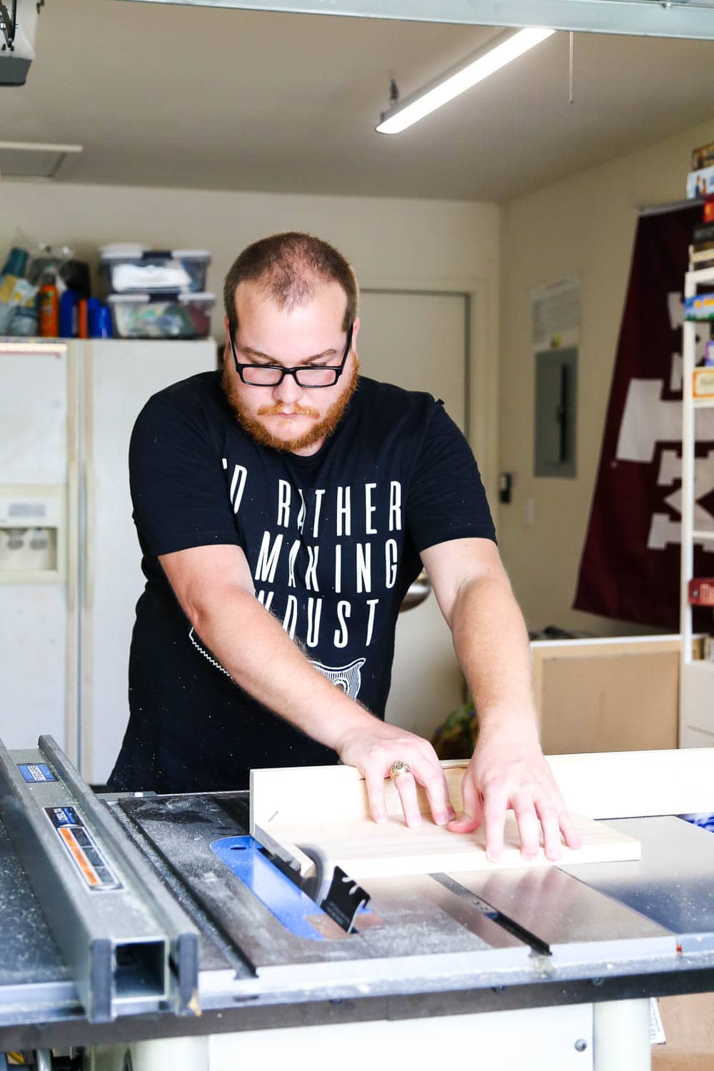 man using a table saw to miter edges of a board