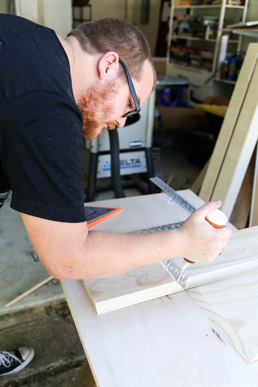 man adding wood glue to pieces for diy fireplace mantel