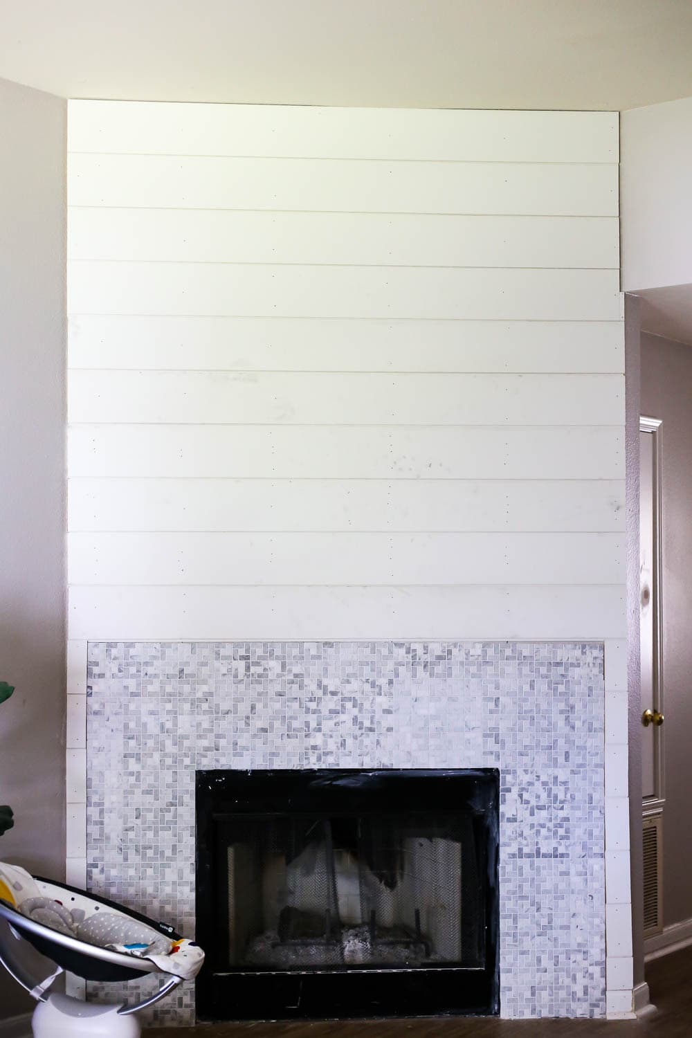 a fireplace wall mid-renovation with fresh tile and unpainted shiplap