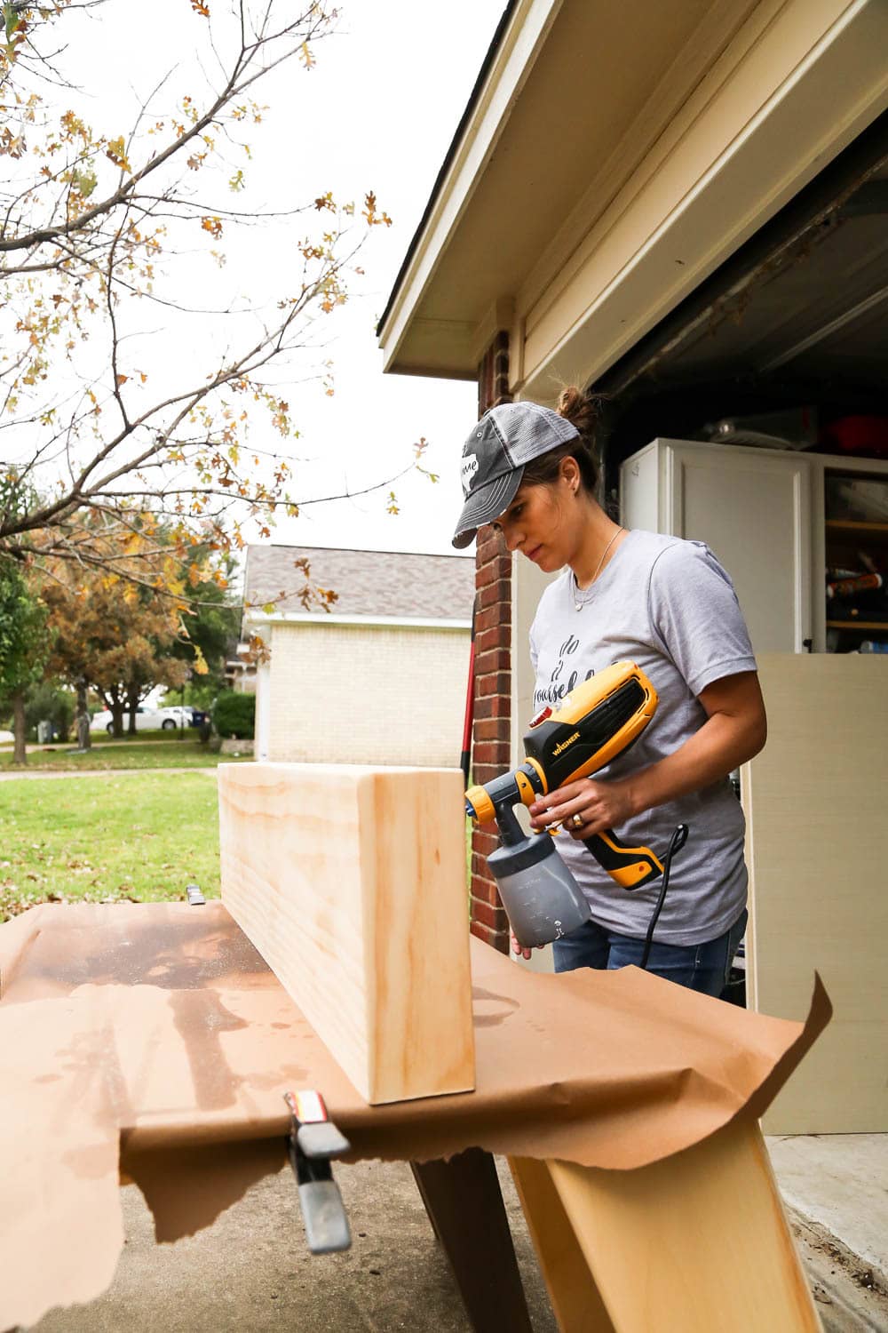 woman staining a shelf with Wagner paint sprayer