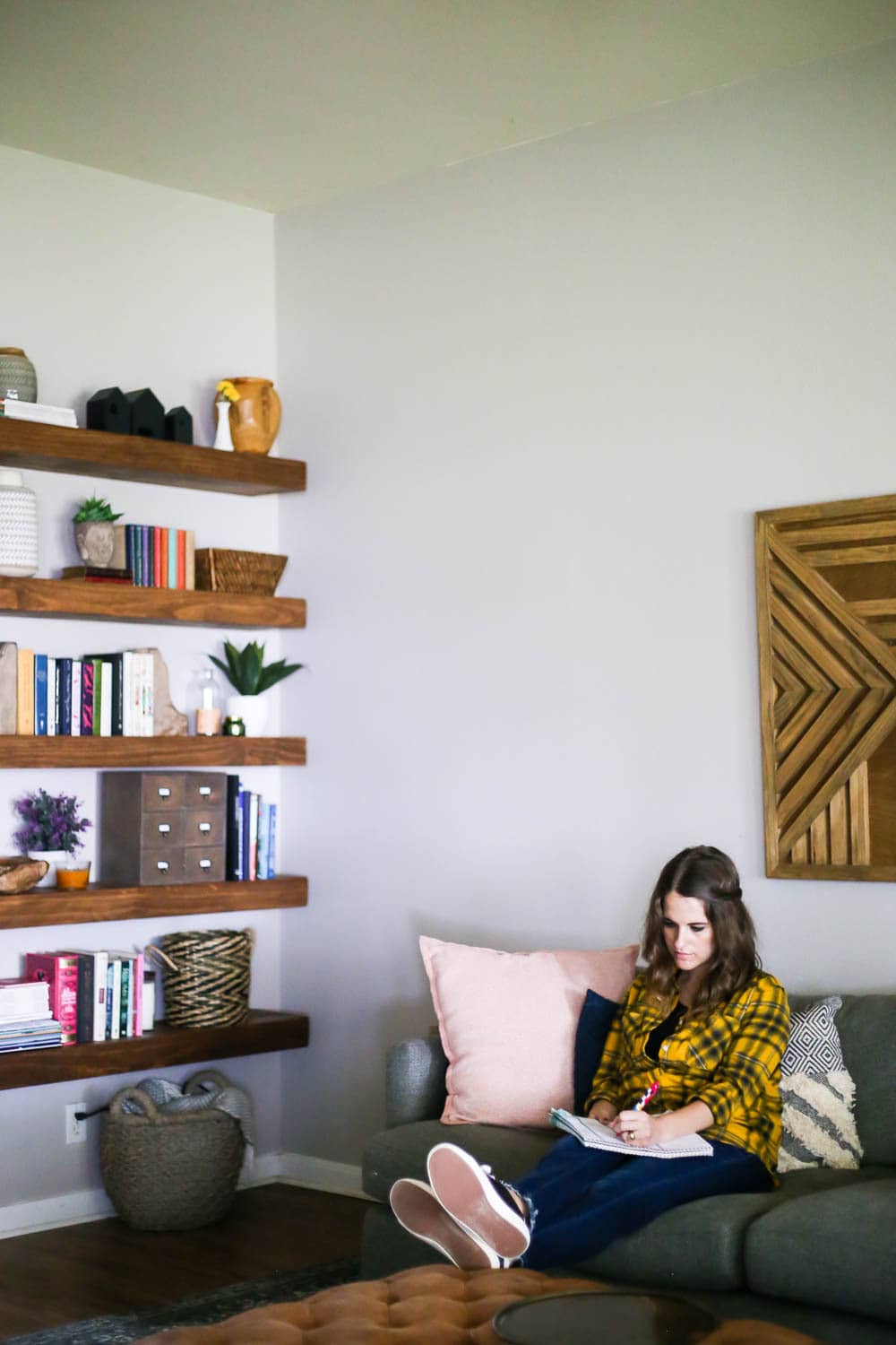 living room with floating shelves and woman on sofa