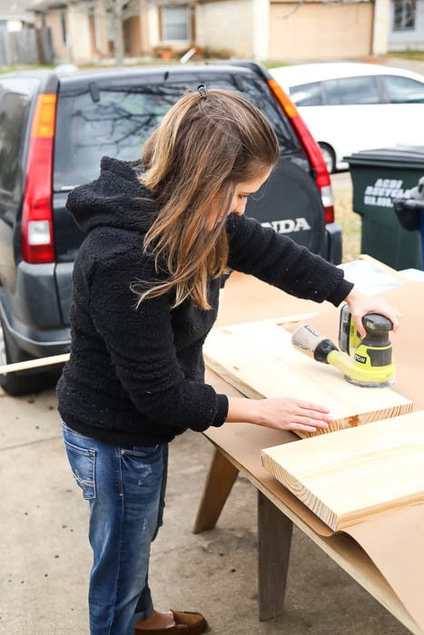 Woman sanding DIY bathroom shelves