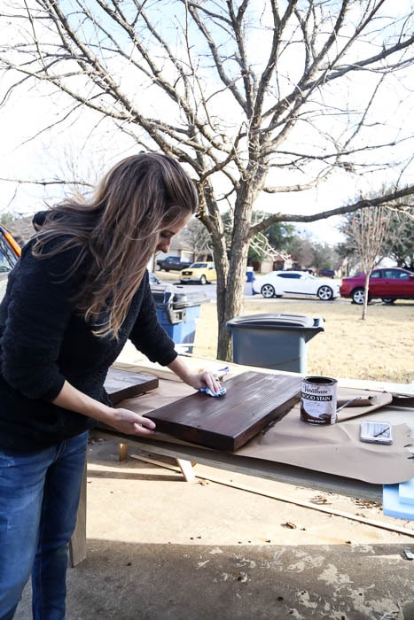 woman using Varathane stain on wood shelves