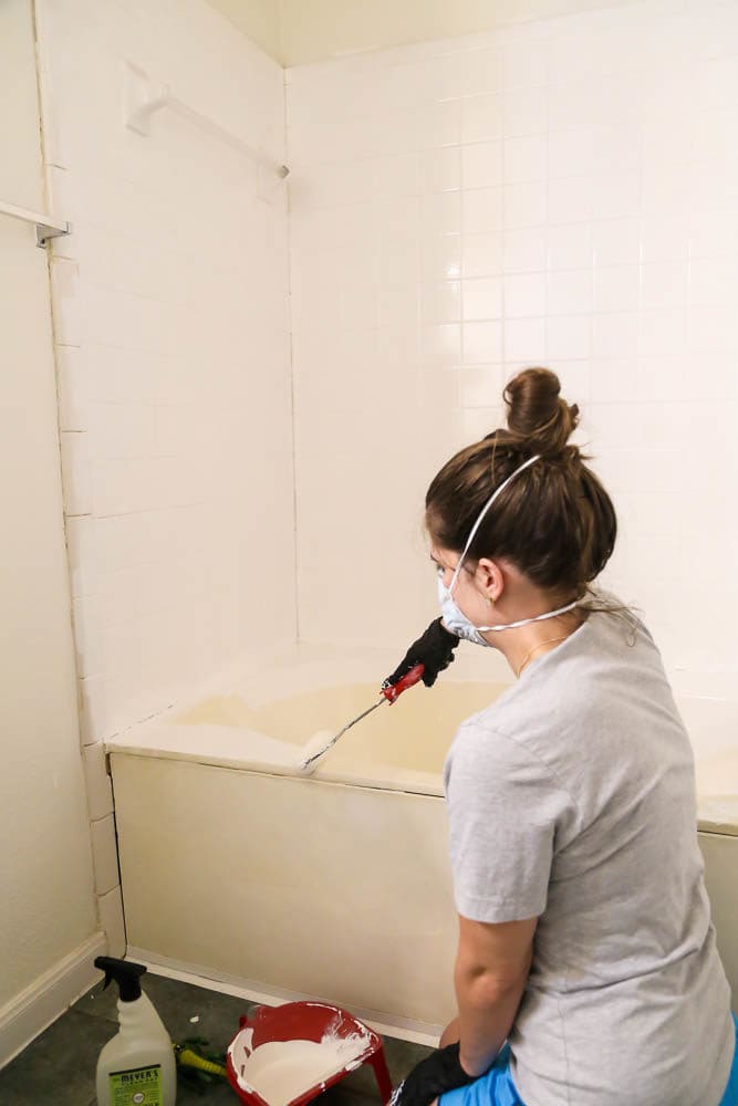 woman rolling white epoxy paint on a bathtub
