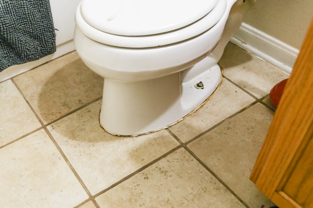 close-up of toilet with stained and cracking grout at base