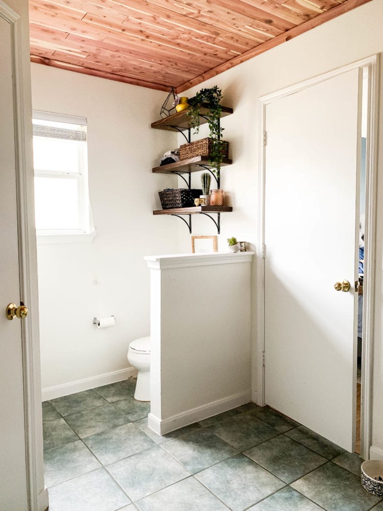 View of a bathroom - toilet and shelving with a cedar-planked ceiling