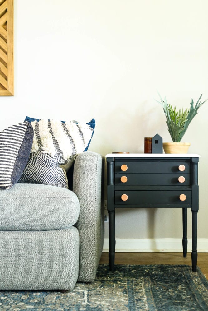 black side table with faux marble top sitting next to a gray couch