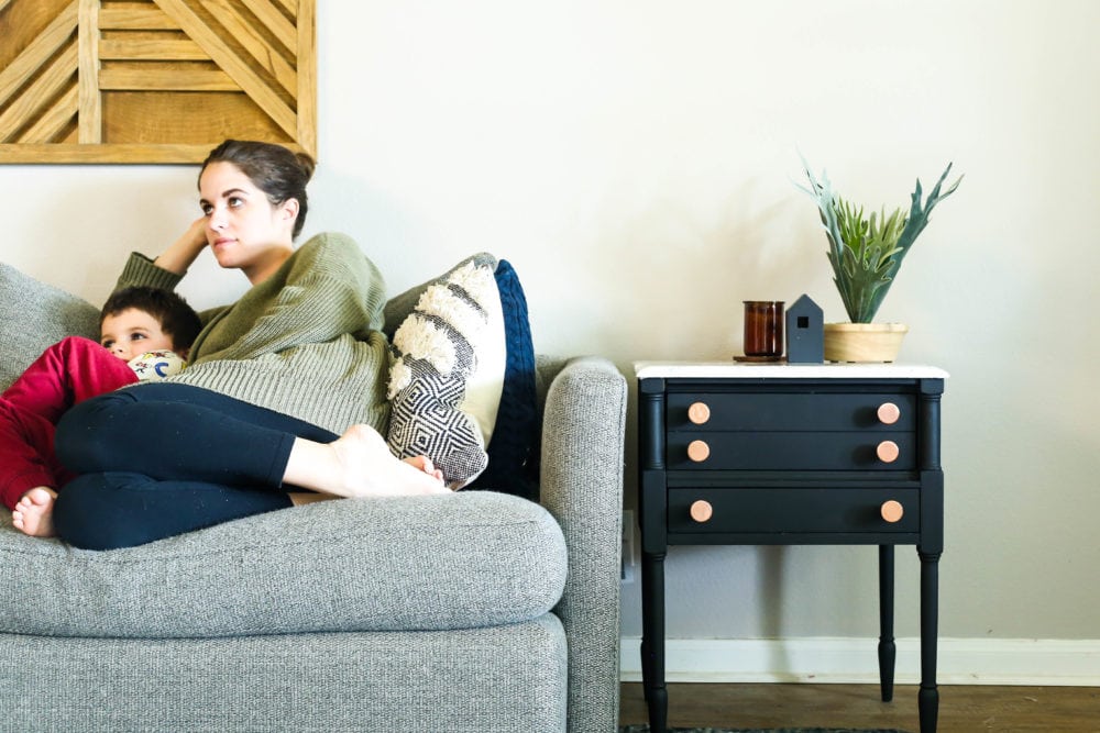 woman and young boy sitting on a gray sofa next to a black side table with a faux marble top.