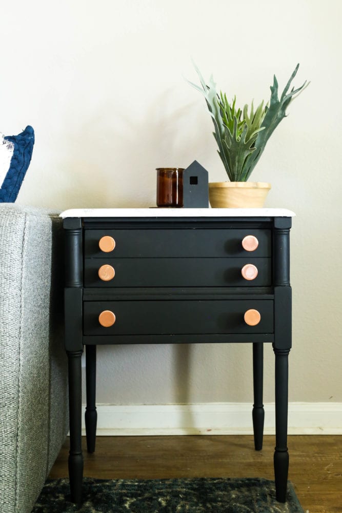 Gray couch next to a black side table with a faux marble top made of contact paper