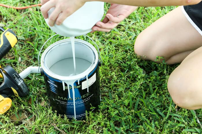 pouring leftover paint from paint sprayer back into paint can
