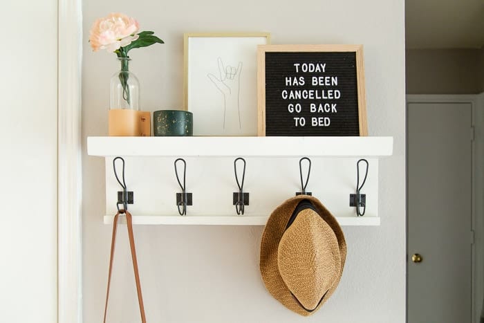 close up of entryway shelf with hooks hanging on a wall