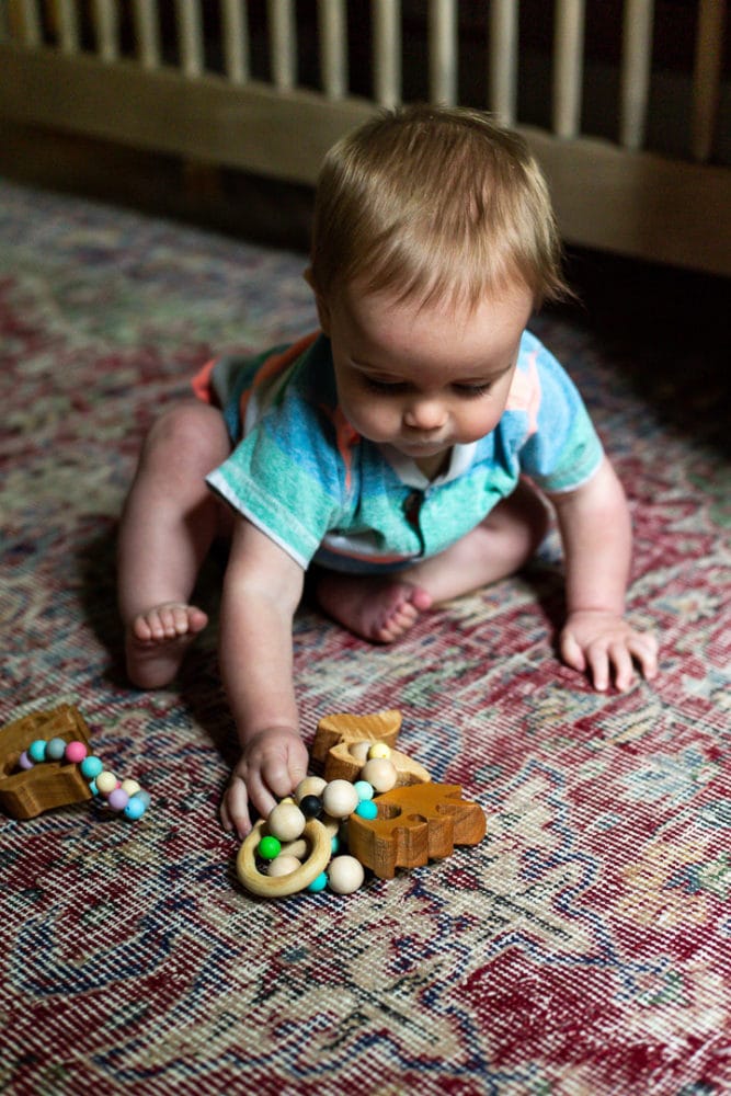 baby playing with wooden animal teethers