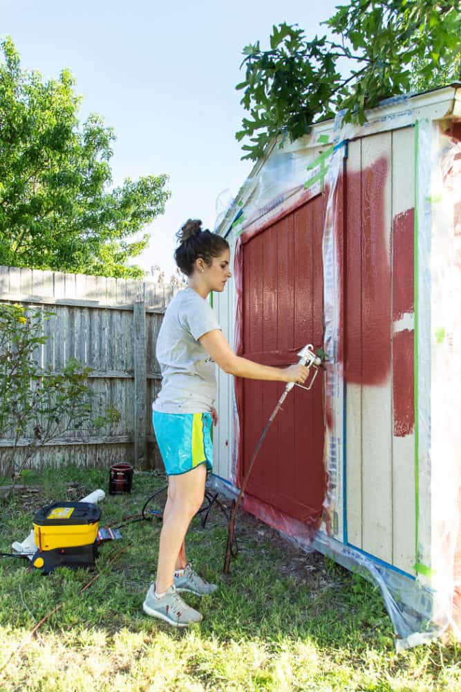 woman painting an outdoor shed