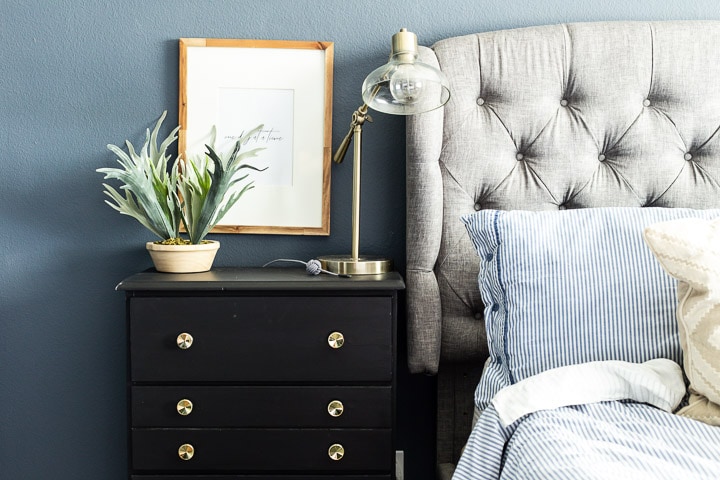 Black dresser sitting in front of a blue wall