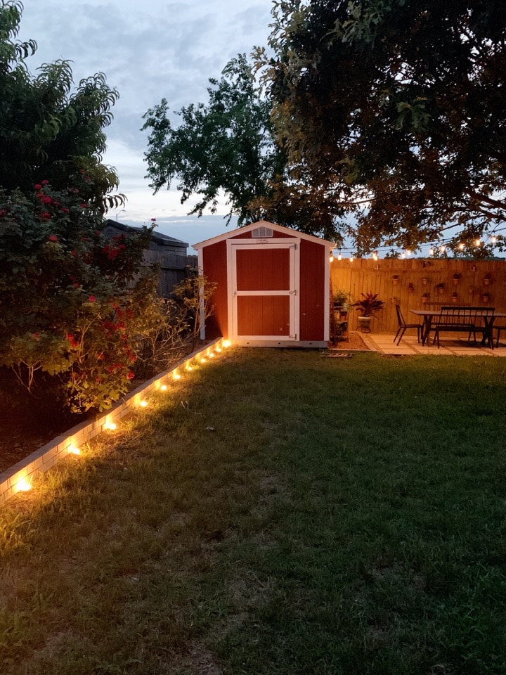 backyard lit up at night with landscape lighting