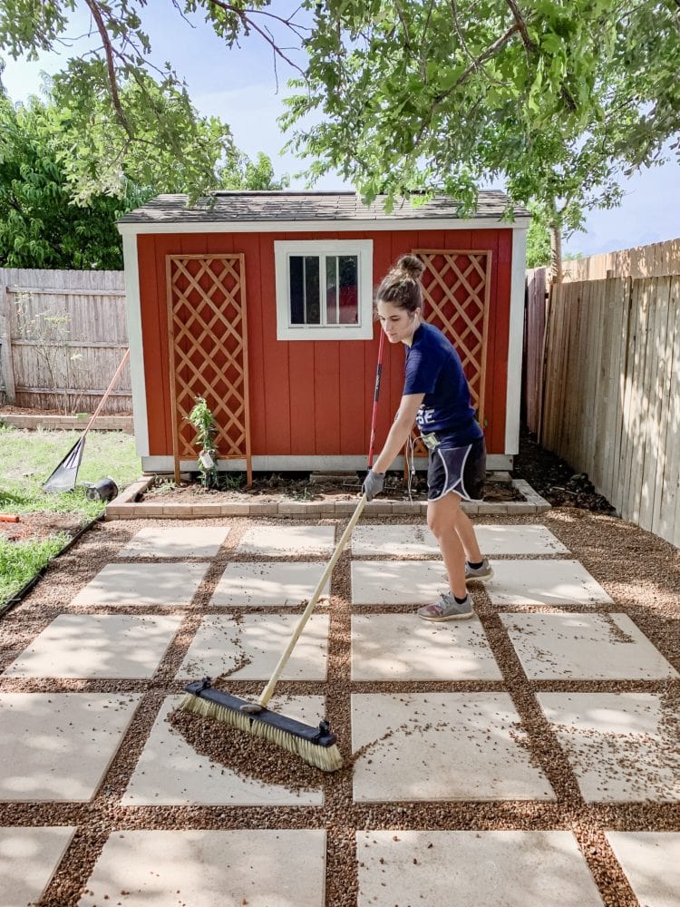 woman sweeping pea gravel into patio