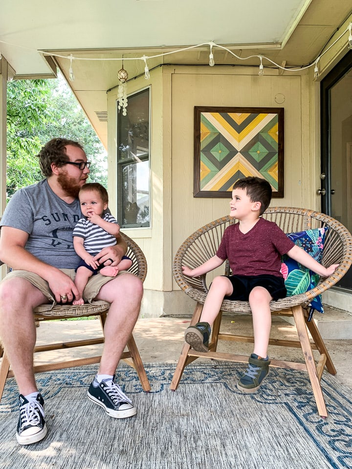 dad talking to two young sons on outdoor patio