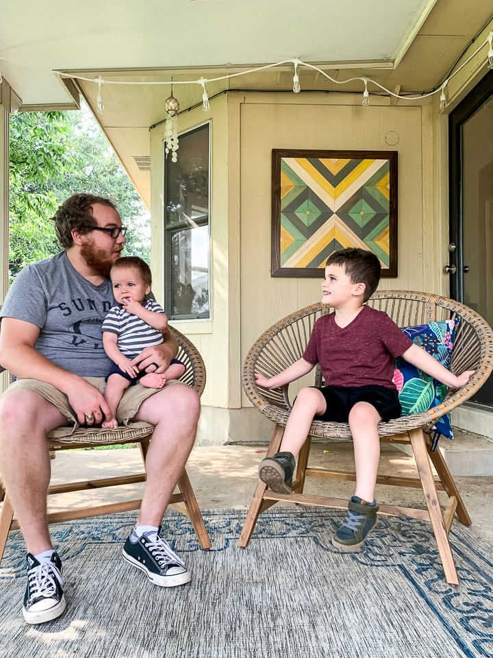 dad talking to two young sons on outdoor patio