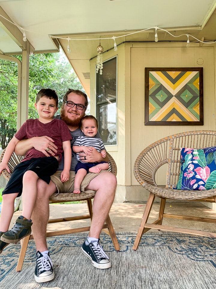 man sitting on a patio with his two young sons